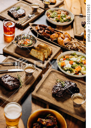 Tasty dishes in restaurant with beef steak, salad and barbecue chicken wings. Food menu concept 108023903