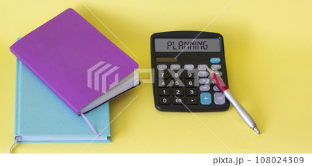 Text on a calculator planning near notepads on a yellow background. Business concept. Text on a calculator planning near notepads on a yellow background. Business concept. 108024309