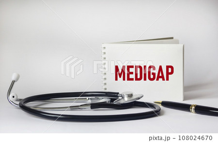 Medigap word on notepad, stethoscope and white background Medigap word on notepad, stethoscope and white background 108024670