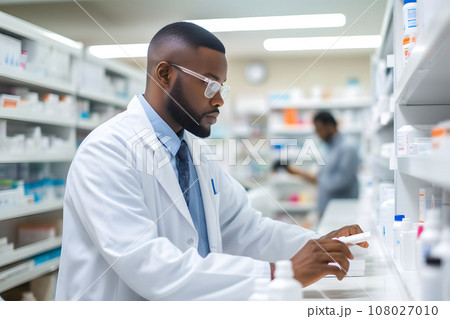 African-American pharmacist in glasses and a white coat checks medicines African-American pharmacist in glasses and a white coat checks medicines 108027010