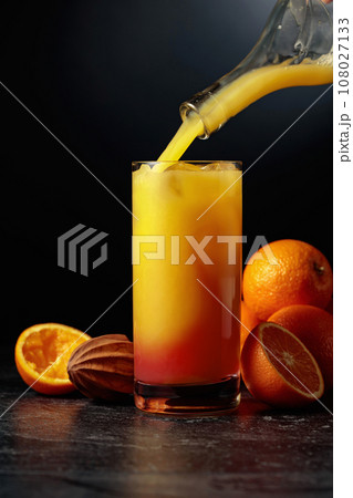 Cocktail Tequila Sunrise with ice and grenadine on a black background. 108027133