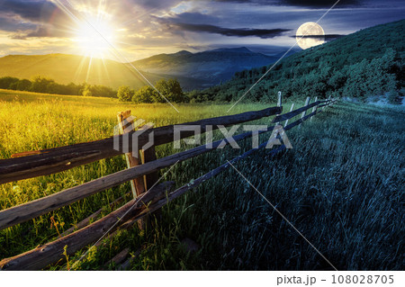 rural landscape with sun and moon at twilight. fence near the meadow and trees on the hillside. day and night time change concept. mysterious countryside scenery in morning light rural landscape with sun and moon at twilight. fence near the meadow and trees on the hillside. day and night time change concept. mysterious countryside scenery in morning light 108028705