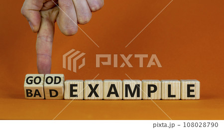 Good or bad example symbol. Businessman turns wooden cubes and changes words 'bad example' to 'good example'. Beautiful orange background. Business and bad or good example concept. Copy space. 108028790