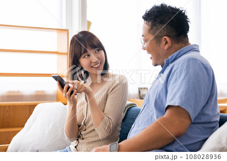 リビングでスマートフォンを使う男女 リビングでスマートフォンを使う男女 108028936