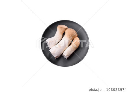 Pleurotus eryngii mushrooms on a dark concrete background 108028974