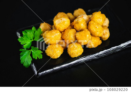 Semifinished Breaded chicken nuggets from chicken fillet on a dark background with fresh herbs. Quick cooking at home. Fast food. Breaded Chicken Inner Fillet. Fast cooking.Chicken nuggets with salad. 108029220