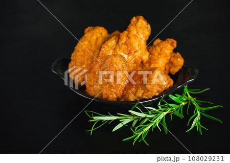 Fast food.Semi-finished chicken wings on a dark background with fresh herbs. Half-finished. Quick cooking at home. Breaded chicken wings.Chicken wings fried until half cooked, semi-finished product. Fast food.Semi-finished chicken wings on a dark background with fresh herbs. Half-finished. Quick cooking at home. Breaded chicken wings.Chicken wings fried until half cooked, semi-finished product. 108029231
