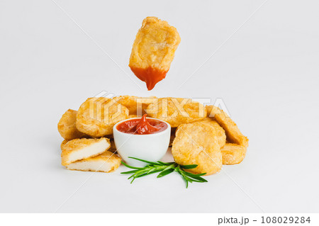 Levitation, breaded chicken nuggets, semi-finished product with fresh herbs on a white background. Fast food. Quick cooking at home. Copy space. 108029284