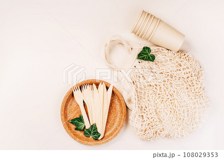 Recycling,eco-friendly concept.Disposable eco cutlery,plates,spoons,knives,forks on a light background.Fabric bag for food delivery.Eco craft paper tableware.Paper cups,fast food containers.Copy space 108029353