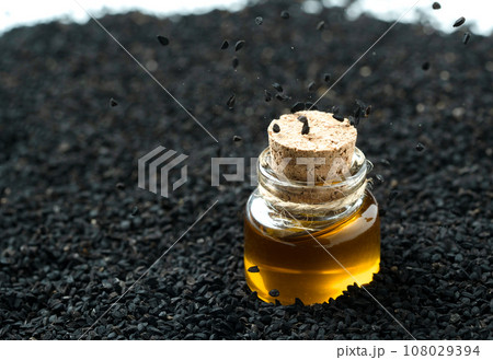 Jar of black cumin oil standing in black cumin seeds 108029394