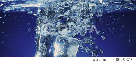 Water splashing and ice cube. Ice splashing into a glass of water. Underwater pouring ice cubes falling into clear watering background. Refreshing chill drinking. Ices in a glass with blue background 108029877