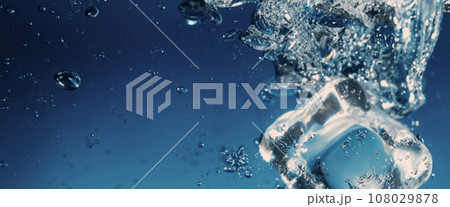 Water splashing and ice cube. Ice splashing into a glass of water. Underwater pouring ice cubes falling into clear watering background. Refreshing chill drinking. Ices in a glass with blue background 108029878