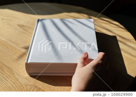 Book mockup, hand opening hardcover on wooden table Book mockup, hand opening hardcover on wooden table 108029900