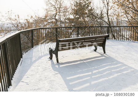 Street bench in the park covered with snow in city or town. Copy space and empty place for text and advertising 108030180