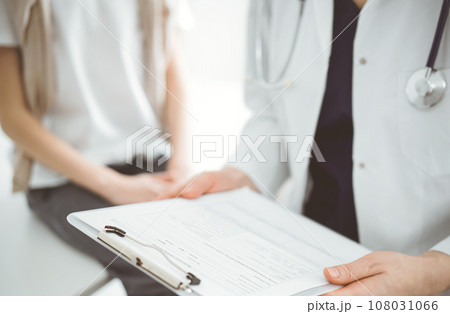 Doctor and child patient. The physician is holding clipboard with medication history records form near a boy. The concept of ideal health in medicine 108031066