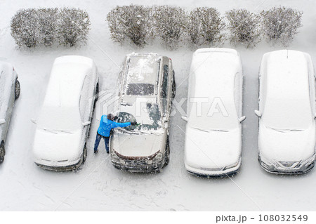 Winter parking lot cars under snow covered cars snow clearing. Parked cars snow removal. Cover winter yard above view top. Courtyard. Winter season. Cold weather conditions. Snowbound. Frosty morning Winter parking lot cars under snow covered cars snow clearing. Parked cars snow removal. Cover winter yard above view top. Courtyard. Winter season. Cold weather conditions. Snowbound. Frosty morning 108032549