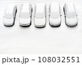 Cover winter parking lot cars under snow covered cars winter season. Snowy row of cars snow background winter time. Top view. Cold weather. Snowbound, Snow weather conditions. Above view. White design 108032551