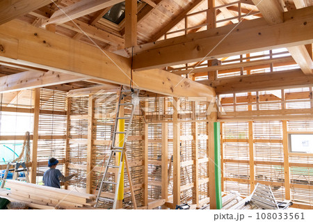 木造住宅の工事現場で土壁の下地に左官工事をする職人さん 108033561