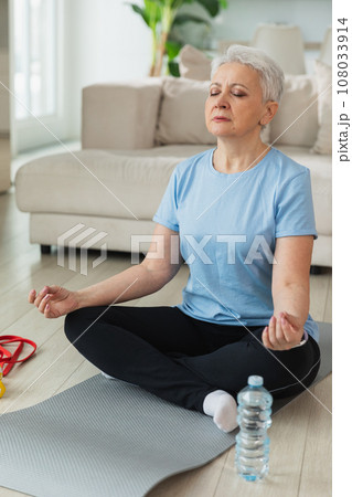 Yoga mindfulness meditation. Senior adult mature woman practicing yoga at home. Mid age old lady sitting in lotus pose on yoga mat meditating relaxing. Older middle aged woman doing breathing practice 108033914