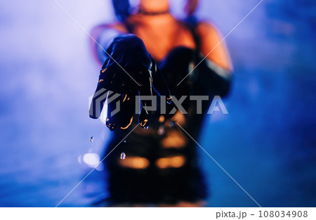 Sexy woman in leather gloves with water drops from night pool under neon light Sexy woman in leather gloves with water drops from night pool under neon light 108034908