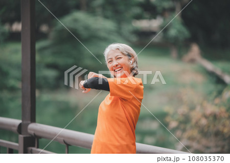 white-haired elderly person exercising in the park early in the morning. 108035370