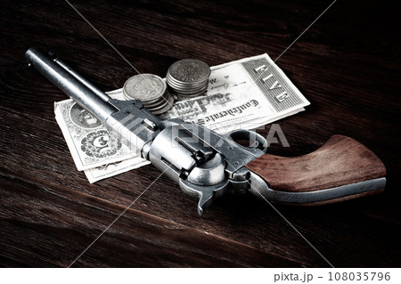 Old west revolver with bill and silver dollars 108035796
