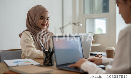 A beautiful Asian-Muslim businesswoman working on a project with her colleague in the office. A beautiful Asian-Muslim businesswoman working on a project with her colleague in the office. 108037812