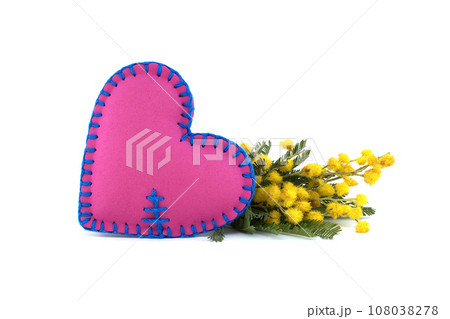 Heart shaped pillow next to yellow mimosa flowers Heart shaped pillow next to yellow mimosa flowers 108038278