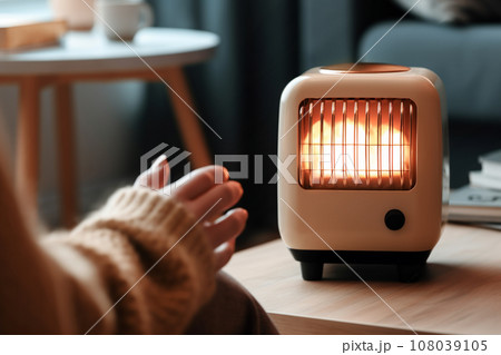 電気ストーブで手を温めるイメージ「AI生成画像」 電気ストーブで手を温めるイメージ「AI生成画像」 108039105