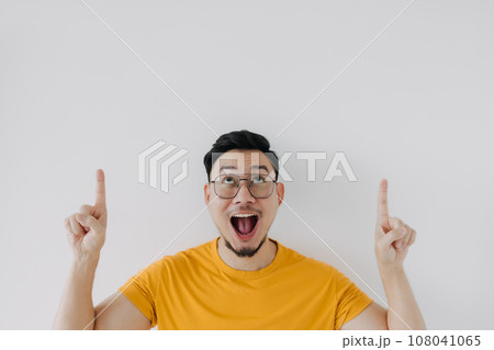 Wow surprised funny face of asian man yellow t-shirt present white copy space 108041065