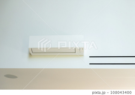 The air conditioner is hanging on the wall in the room The air conditioner is hanging on the wall in the room 108043400