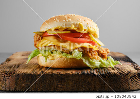 Chicken cheeseburger with fresh and pickled vegetables, front view Chicken cheeseburger with fresh and pickled vegetables, front view 108043942