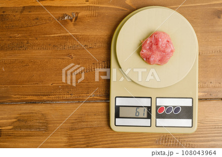 Weighting minced meat on a kitchen scales Weighting minced meat on a kitchen scales 108043964