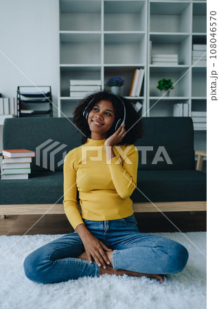 Happy young African American latina woman listening to music using headphones at home living room. relaxing, relax, relaxation concepts. 108046570