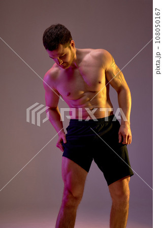 strong sportsman looking at his biceps on legs strong sportsman looking at his biceps on legs 108050167