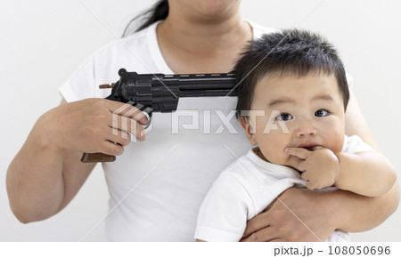 玩具の拳銃を頭に当てられた赤ちゃん(男の子、0歳、生後10カ月、日本人)。人質のイメージ 玩具の拳銃を頭に当てられた赤ちゃん(男の子、0歳、生後10カ月、日本人)。人質のイメージ 108050696