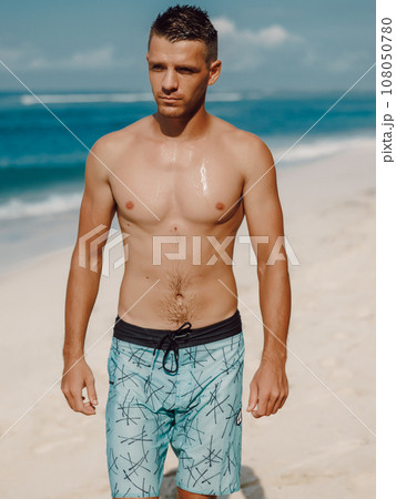 Handsome muscular man shirtless on the beach, summer time. Ideal slim fit body. Handsome muscular man shirtless on the beach, summer time. Ideal slim fit body. 108050780