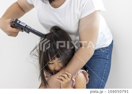 玩具の拳銃を頭に当てられた笑顔の女の子（3歳、日本人） 108050791