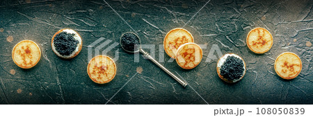 Blinis with black caviar and cream cheese panorama on a black slate background 108050839