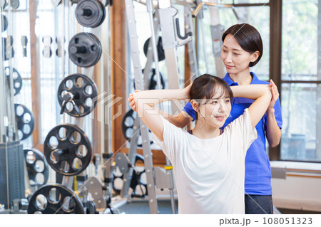 スポーツジムでパーソナルストレッチを受ける女性 108051323