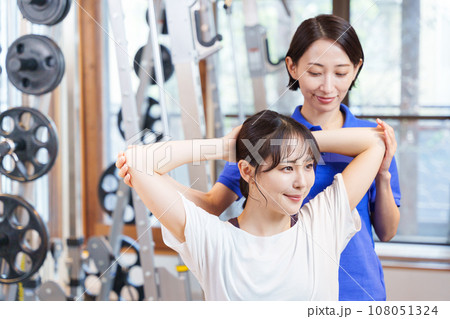 スポーツジムでパーソナルストレッチを受ける女性 108051324