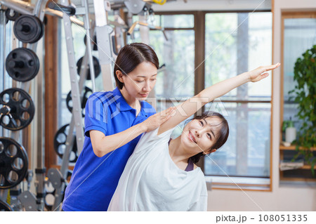 スポーツジムでパーソナルストレッチを受ける女性 108051335
