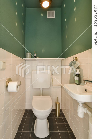 a bathroom with green walls and white tiles on the floor, along with a toilet in the corner of the room 108052077