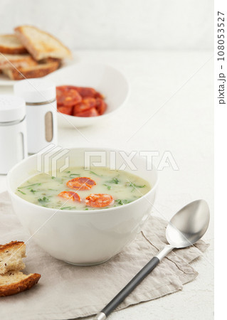 Typical Portuguese soup Caldo Verde with bread and chorizo sausage on white background Typical Portuguese soup Caldo Verde with bread and chorizo sausage on white background 108053527