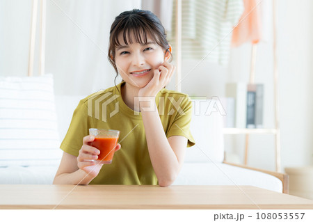 リビングで野菜ジュースを飲む若い女性 108053557