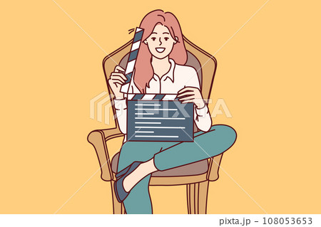 Woman film producer holds clapperboard and smiles sitting in chair to invite participate in casting 108053653