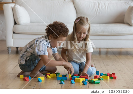 Two focused little kids playing on floor at home 108053880