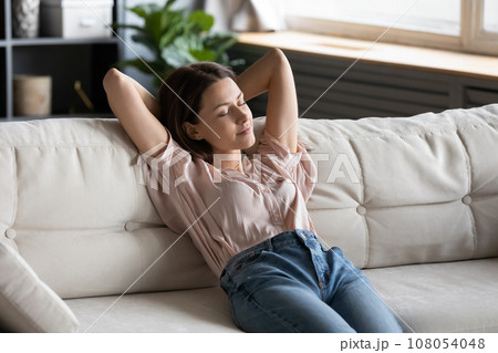 Relaxed housewife completed chores reduces tiredness leaned on couch Relaxed housewife completed chores reduces tiredness leaned on couch 108054048