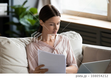 Workaholic woman on weekend working at home seated on couch 108054212