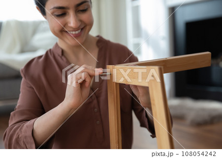 Close up smiling Indian woman assembling new wooden furniture 108054242